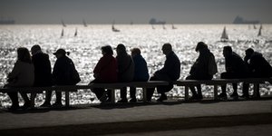 Κόσμος σε παγκάκι μπροστά από θάλασσα