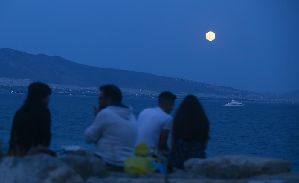 Παρέα απολαμβάνει την Πανσέληνο το βράδυ της Παρασκευής από τον Πειραιά