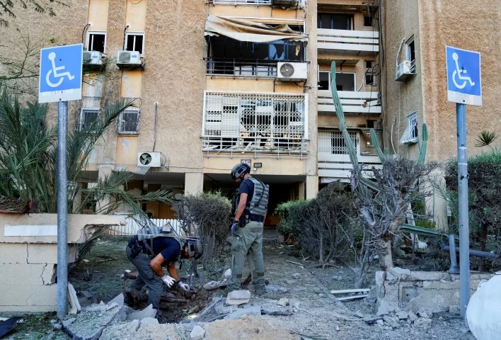 Μέλη της ομάδας εξουδετέρωσης εκρηκτικών του Ισραήλ επιθεωρεί σημείο που έπληξε πύραυλος της Χαμάς στην Ασκελόν -Φωτογραφία: AP Photo/Tsafrir Abayov