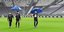Παίκτες της Γιουβέντους κάνουν βόλα εντός γηπέδου κρατώντας ομπρέλες 