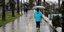 Γυναίκα περπατά με ομπρέλα σε πεζόδρομο 