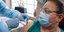 εμβόλιο σε γυναίκα με γυαλιά και μάσκα από νοσηλευτή με γάντια