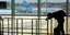 ανδρας σκυφτός σε κουπαστή σε αεροδρόμιο στην Κύπρο με αεροπλάνα σε αεροδιάδρομο, 