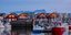 Θέα της μαρίνας, των αλιευτικών σκαφών και των τυπικών ξύλινων σκανδιναβικών σπιτιών με αντανάκλαση στο νερό μετά το ηλιοβασίλεμα