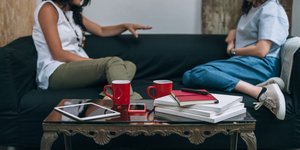 Δύο γυναίκες κάθονται αντικριστά και μιλούν καθισμένες στον καναπέ
